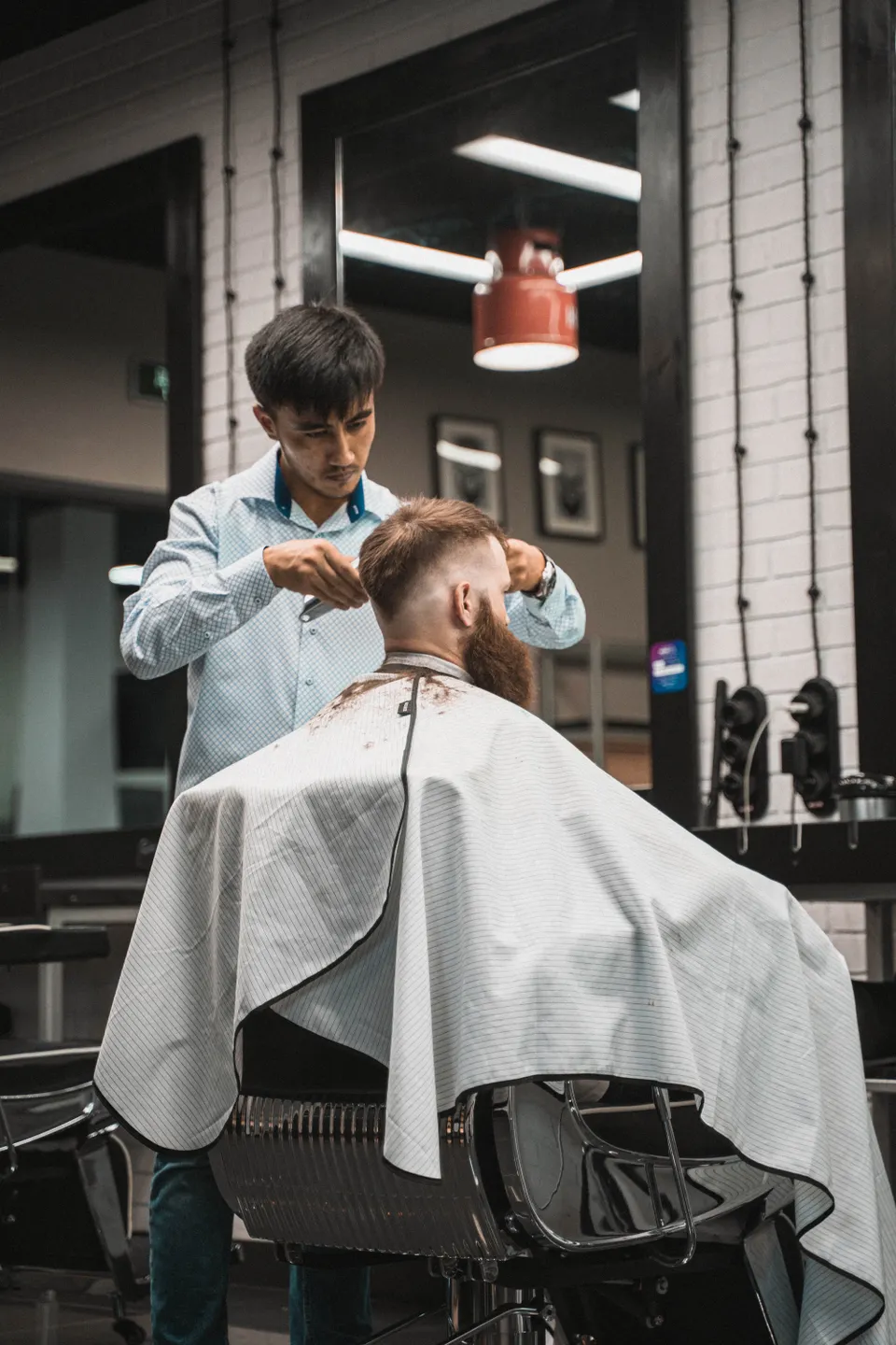 آرایشگر در حال کوتاهی موی یک مرد در آرایشگاه؛ عکس آرشیوی